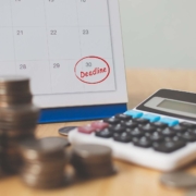 Calculator-with-calendar_ Coins, a calculator, and a day circled deadline on a calendar