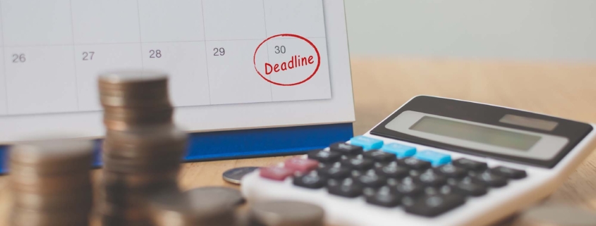Coins, a calculator, and a day circled deadline on a calendar
