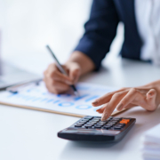 Close-up-of-the-hands-of-a-business-woman-using-a-calculator-to-check-financial-accounts-check-the-companys-expenses-and-budget_ Close-up of the hands of a business woman using a calculator to check financial accounts check the company's expenses and budget_