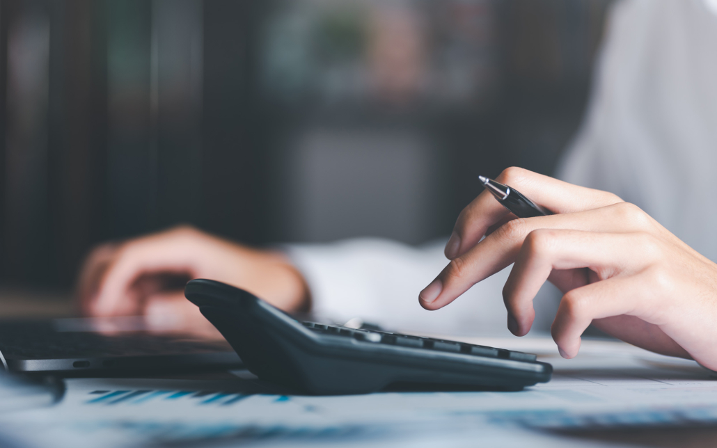 Hand with pen inputting numbers on a calculator