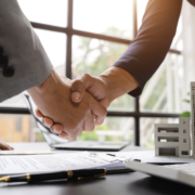 Two business people handshaking in a windowed office room
