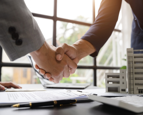 Two business people handshaking in a windowed office room