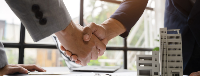 Two business people handshaking in a windowed office room