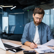 spectacled man looking at papers and doing finances