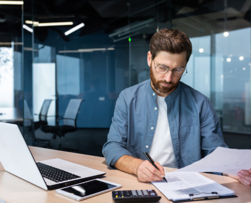 spectacled man looking at papers and doing finances