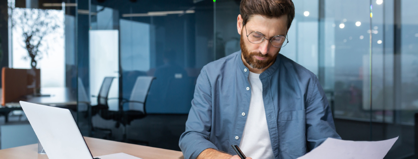 spectacled man looking at papers and doing finances