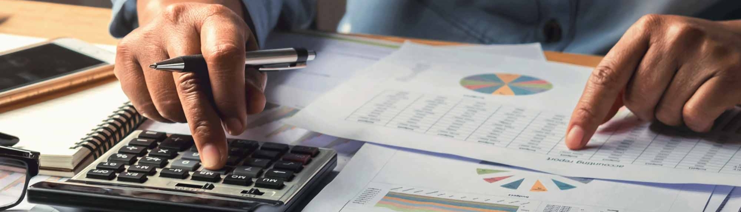 person in blue shirt using calculator and looking at financial report