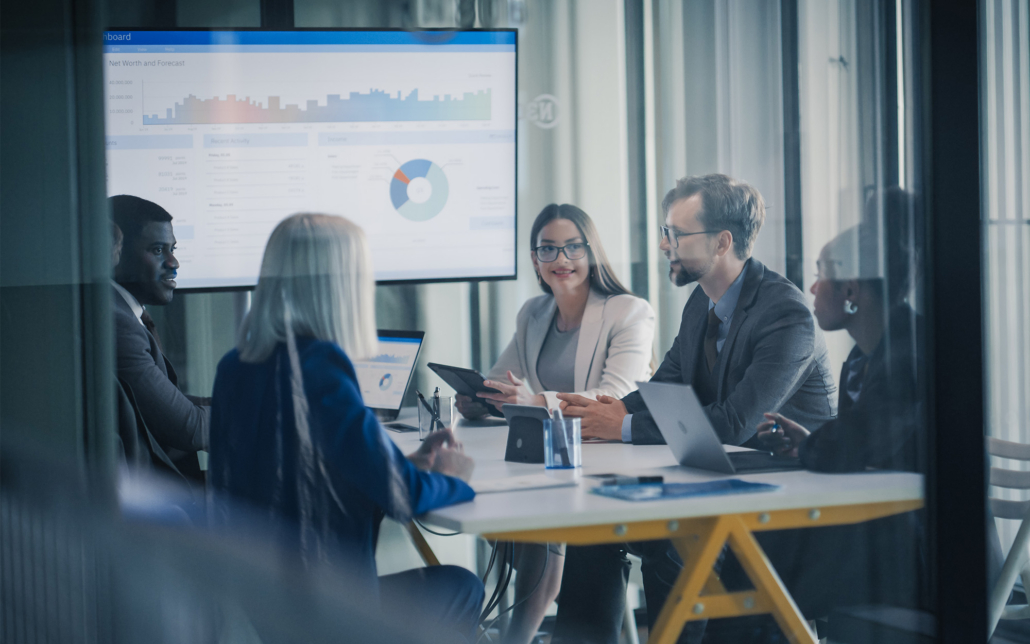 Business Team Meets In A Glass Conference Room To Review Dashboards