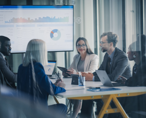 Business Team Meets In A Glass Conference Room To Review Dashboards
